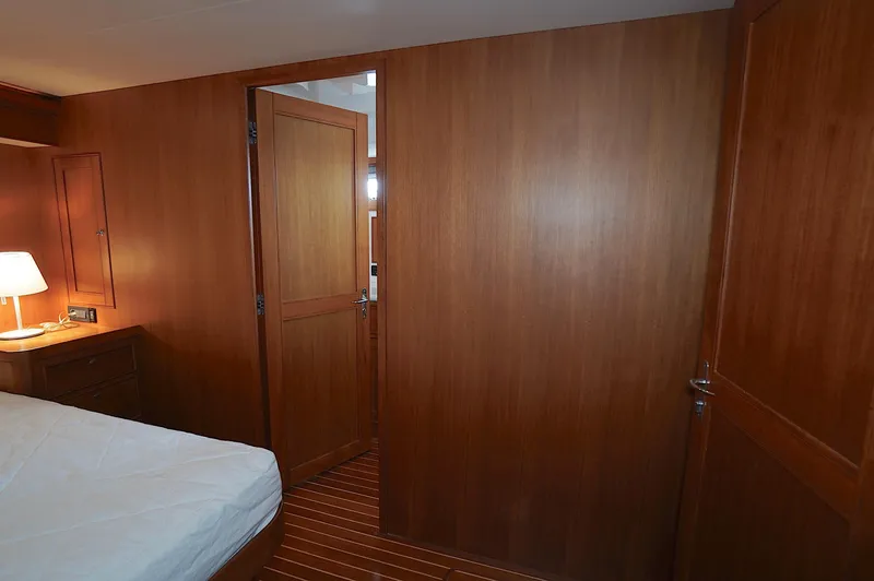 Defly Yacht Photos Pics Wood-paneled cabin interior of 2009 Marlow 61E yacht with bed and lamp.