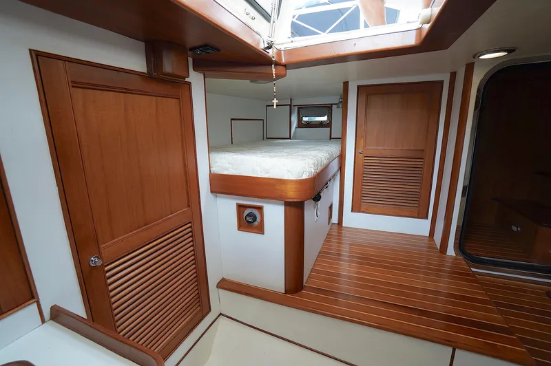 Defly Yacht Photos Pics Interior of 2009 Marlow 61E yacht with wooden finishes and a cozy bed.