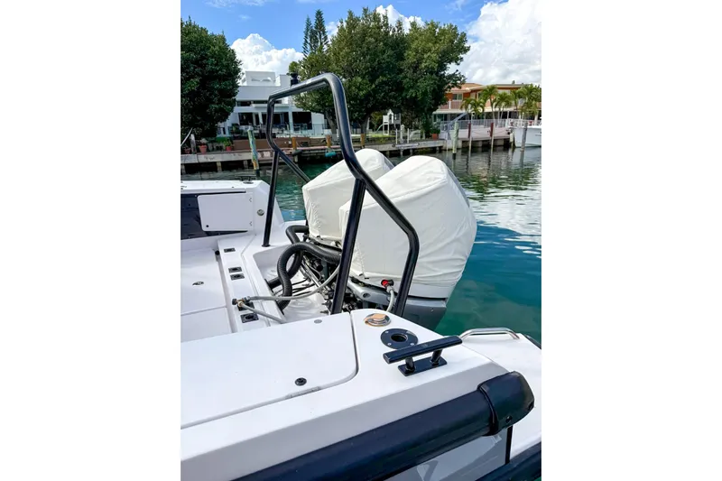  Yacht Photos Pics 2023 Axopar 37 XC Cross Cabin boat with covered outboard motor, docked by waterfront homes.