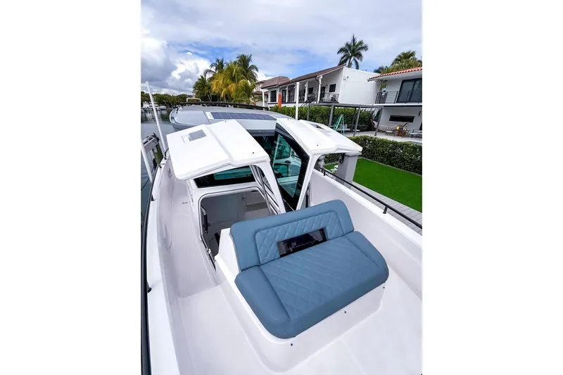  Yacht Photos Pics 2023 Axopar 37 XC Cross Cabin with blue seating, docked near waterfront homes.