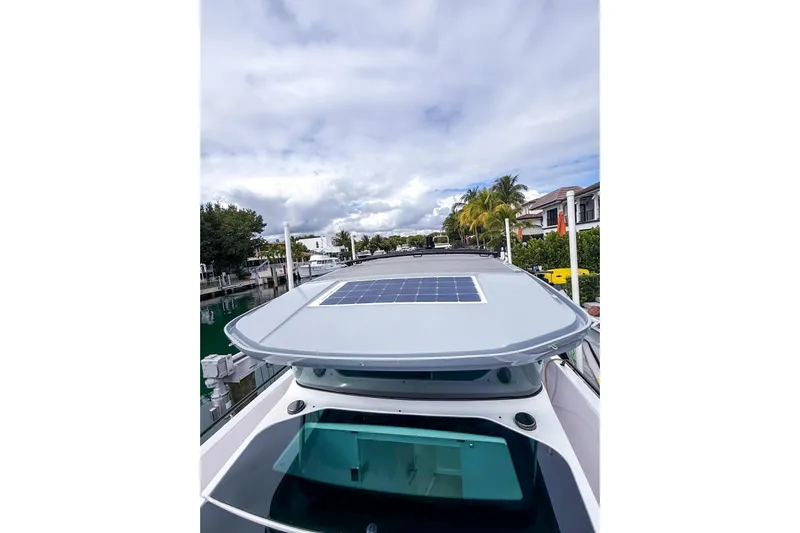  Yacht Photos Pics 2023 Axopar 37 XC Cross Cabin with solar panel on roof, docked by waterfront homes.