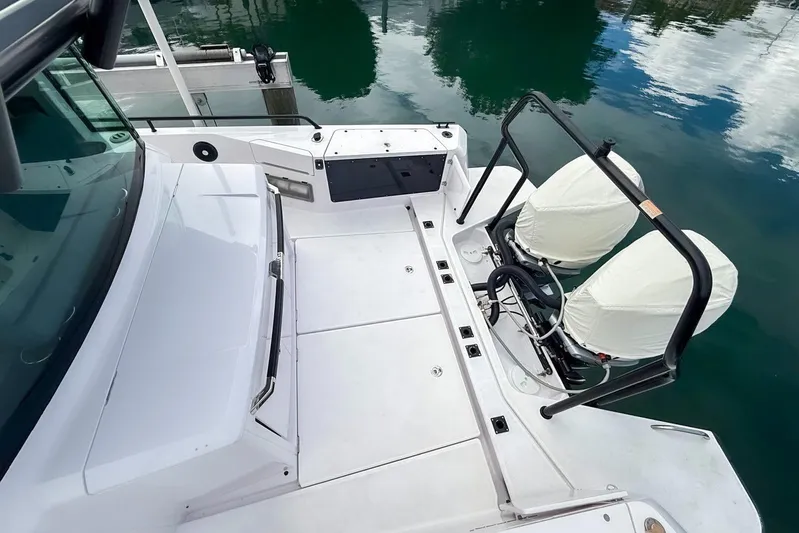  Yacht Photos Pics 2023 Axopar 37 XC Cross Cabin boat deck with covered engines, docked on calm water.