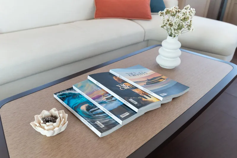 Yacht Photos Pics Coffee table with magazines, decorative flower, and vase on Lagoon SIXTY 5 yacht, 2024 model.