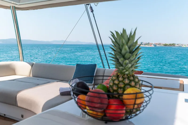  Yacht Photos Pics Luxurious Lagoon SIXTY 5 yacht interior with fruit basket, overlooking serene ocean view, 2024 model.