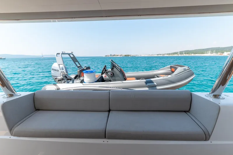  Yacht Photos Pics 2024 Lagoon SIXTY 5 yacht with tender boat on serene blue water.