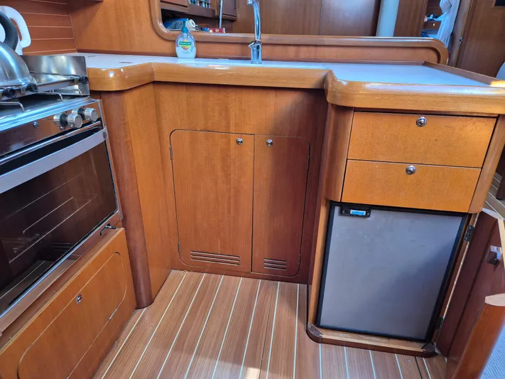 Princess Yacht Photos Pics Wooden kitchen interior of 2008 Grand Soleil 45 yacht with stove, sink, and mini fridge.