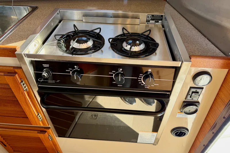  Yacht Photos Pics 2012 Ranger Tugs R-29 kitchen stove with dual burners and oven, featuring wooden cabinetry.
