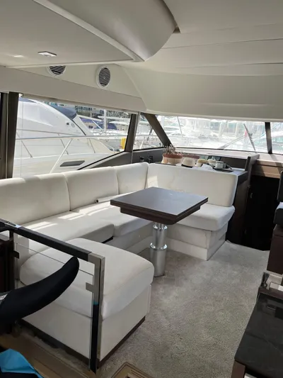 Simorgh Yacht Photos Pics Interior of a 2019 Prestige 460 yacht with white seating and a dining table.