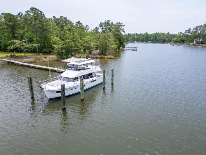 Sweetest Southern Comfort Yacht Photos Pics 2022 Beneteau ST48 Swift Trawler 48 docked on a serene river with lush greenery.