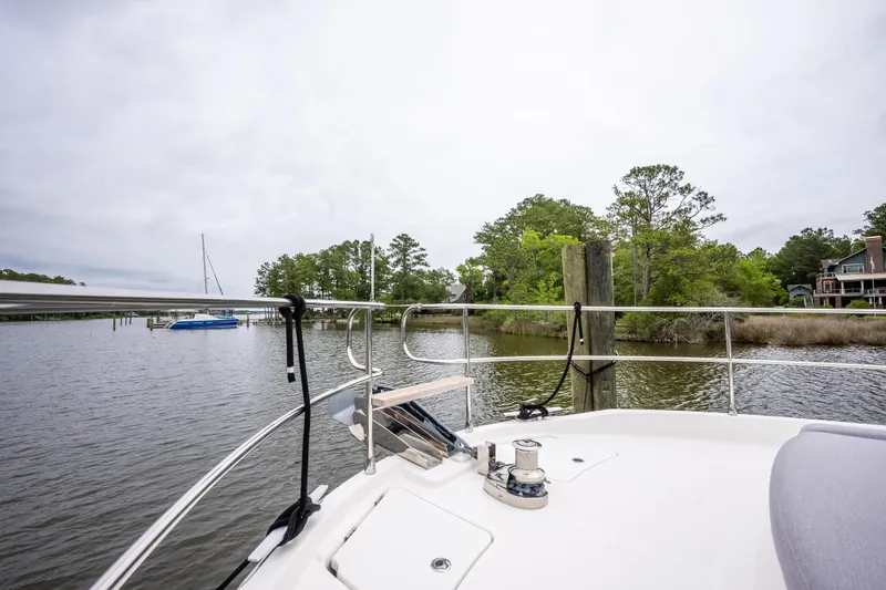 Sweetest Southern Comfort Yacht Photos Pics Bow view of 2022 Beneteau ST48 Swift Trawler 48 docked near lush shoreline.