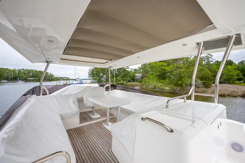 Sweetest Southern Comfort Yacht Photos Pics Outdoor seating area on 2022 Beneteau ST48 Swift Trawler, featuring covered deck and scenic waterway view.