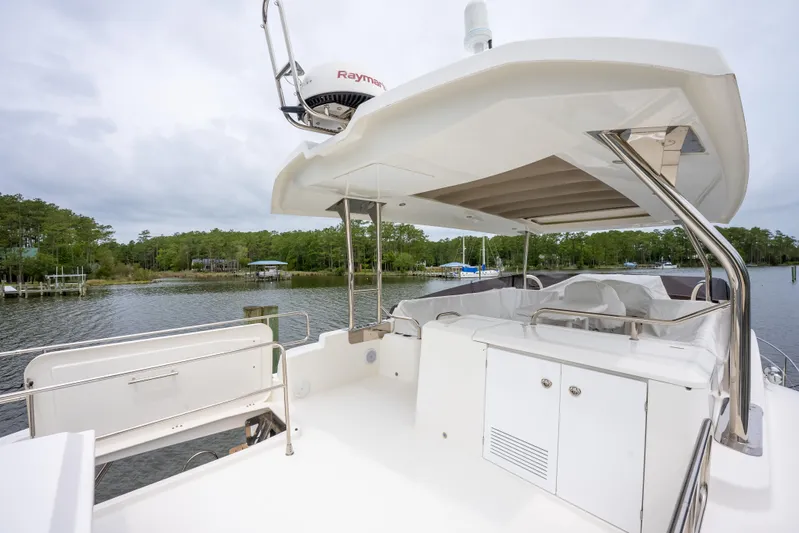 Sweetest Southern Comfort Yacht Photos Pics 2022 Beneteau ST48 Swift Trawler 48, spacious deck with canopy, docked by lush greenery.