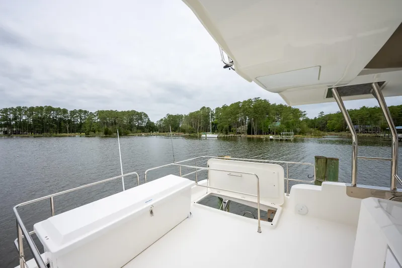 Sweetest Southern Comfort Yacht Photos Pics Beneteau ST48 Swift Trawler 48, 2022 model, docked by a serene lake with lush greenery.