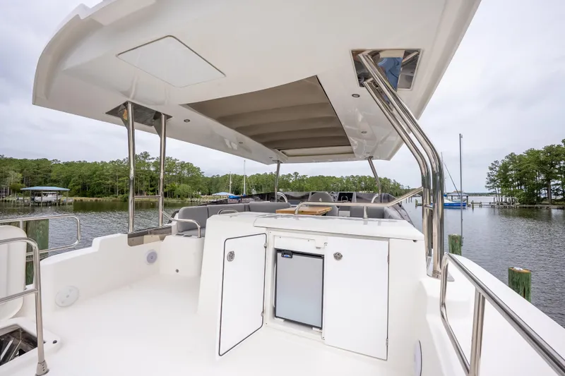 Sweetest Southern Comfort Yacht Photos Pics 2022 Beneteau ST48 Swift Trawler 48 deck with seating and storage, docked by a scenic waterfront.