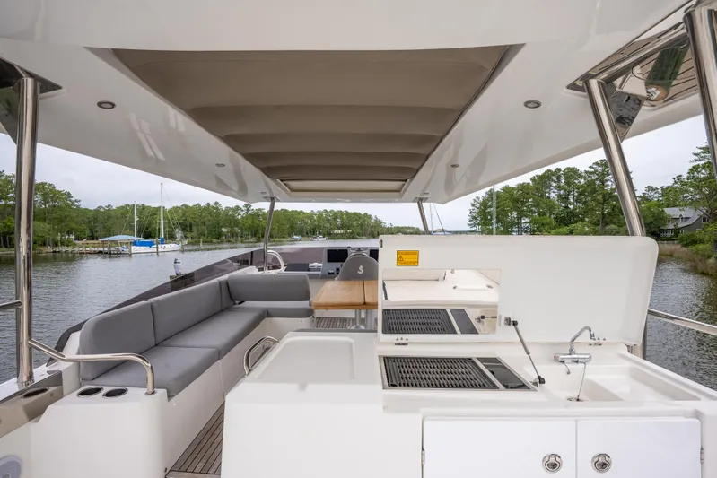 Sweetest Southern Comfort Yacht Photos Pics Flybridge of 2022 Beneteau ST48 Swift Trawler with seating and outdoor kitchen, docked by trees.