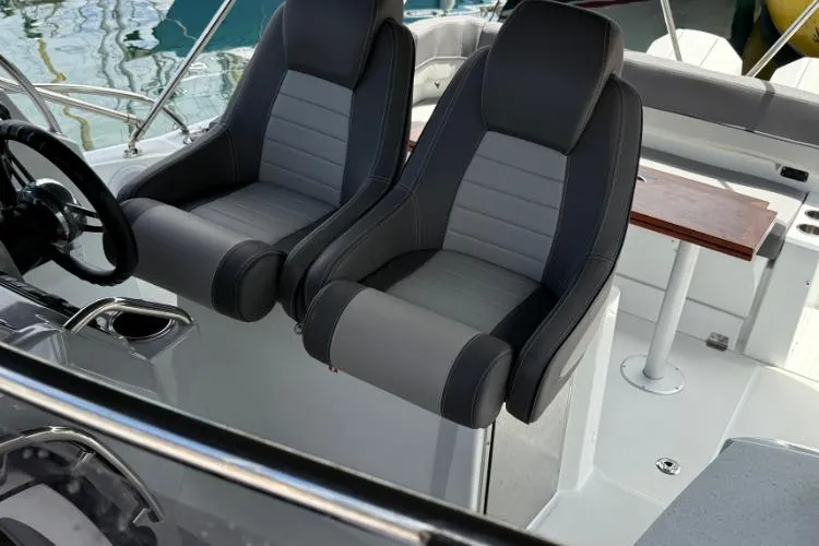 P'tit Bateau Yacht Photos Pics 2022 Jeanneau Cap Camarat 9.0 WA boat interior with dual gray seats and steering wheel.