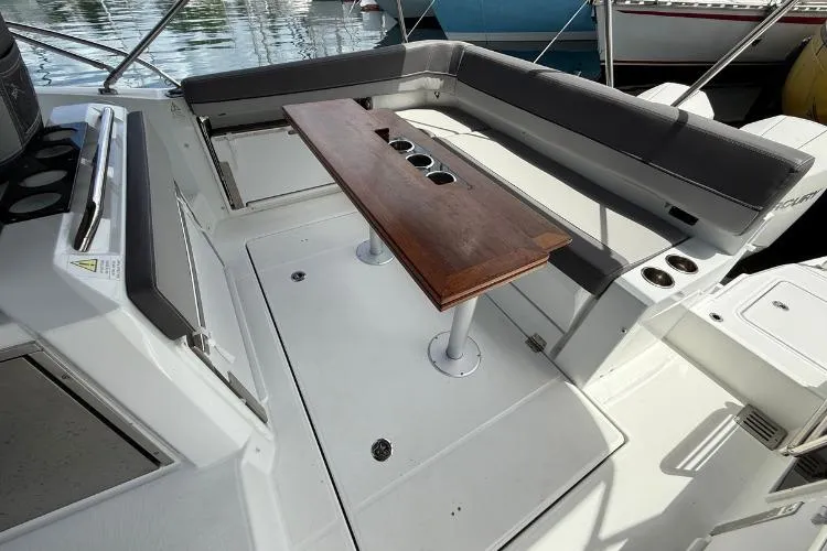 P'tit Bateau Yacht Photos Pics 2022 Jeanneau Cap Camarat 9.0 WA boat interior with seating and wooden table.