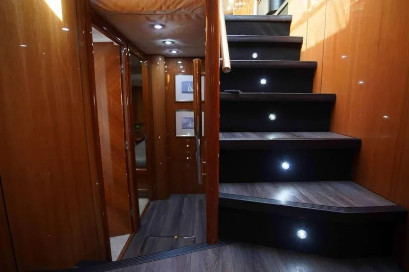 Fins Up Yacht Photos Pics Luxurious interior staircase of 2006 Sunseeker Manhattan Motor 82 yacht with wood paneling and LED lights.