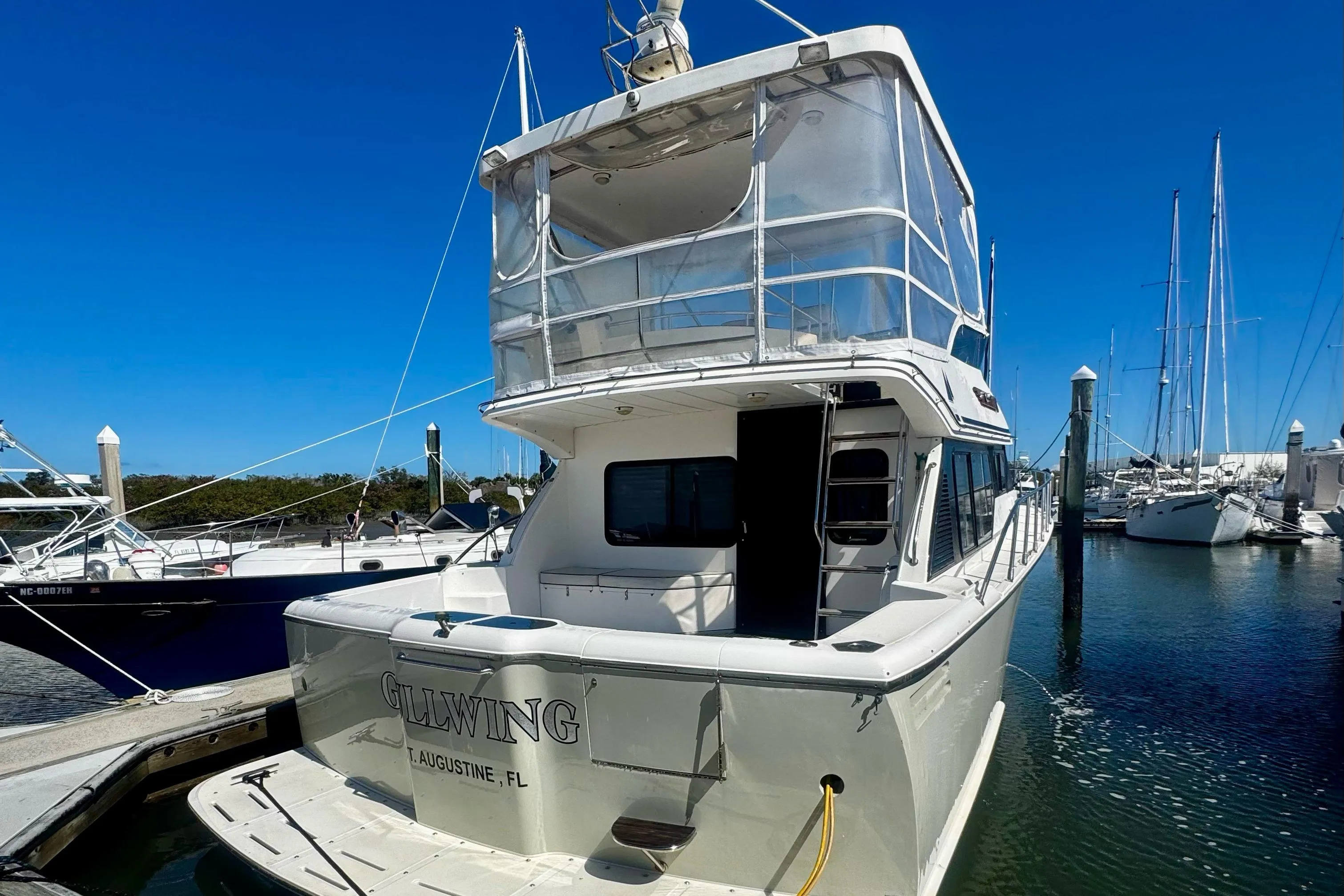 1998 Mikelson 43 Sportfisher docked at marina under clear blue sky.