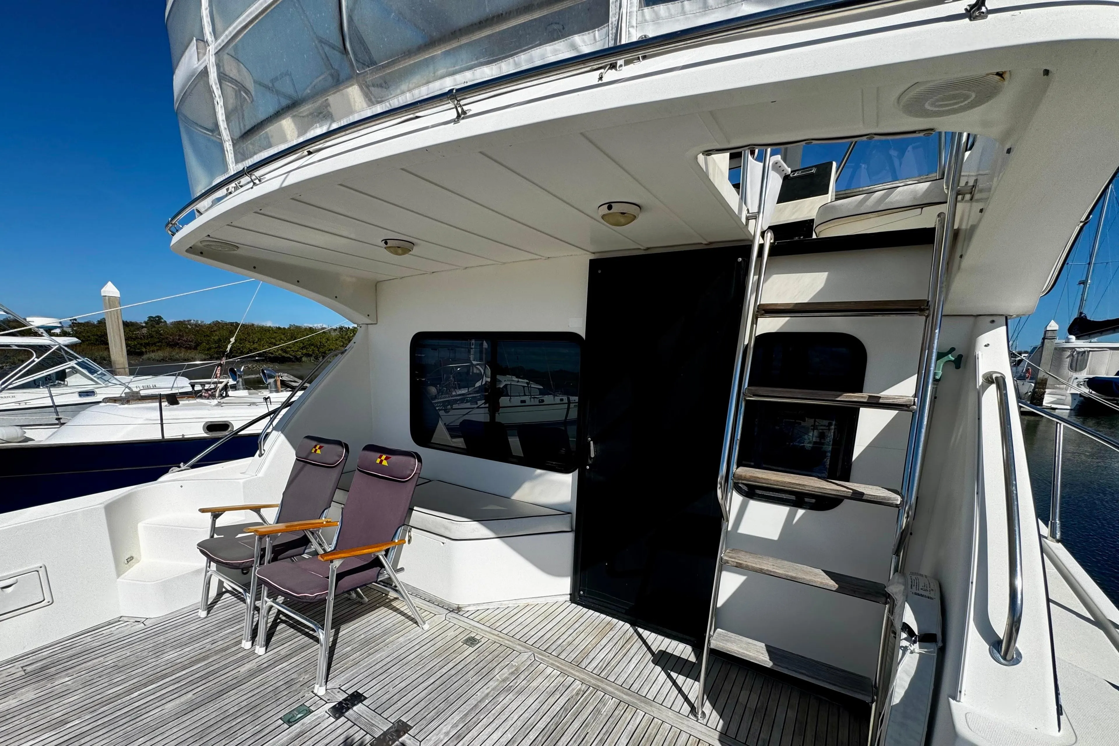 1998 Mikelson 43 Sportfisher yacht deck with chairs and ladder under clear blue sky.