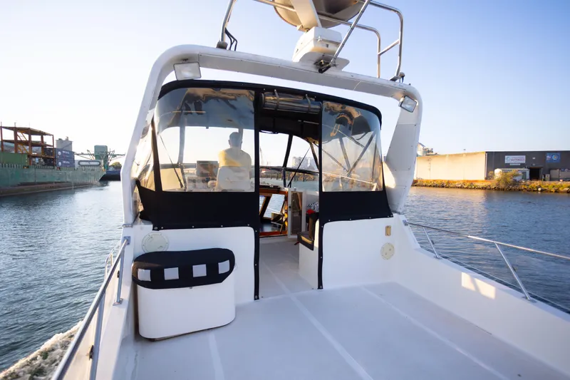 Mbellish Yacht Photos Pics 1988 Symbol 51 Motoryacht cruising in a canal, featuring a spacious deck and enclosed cockpit.