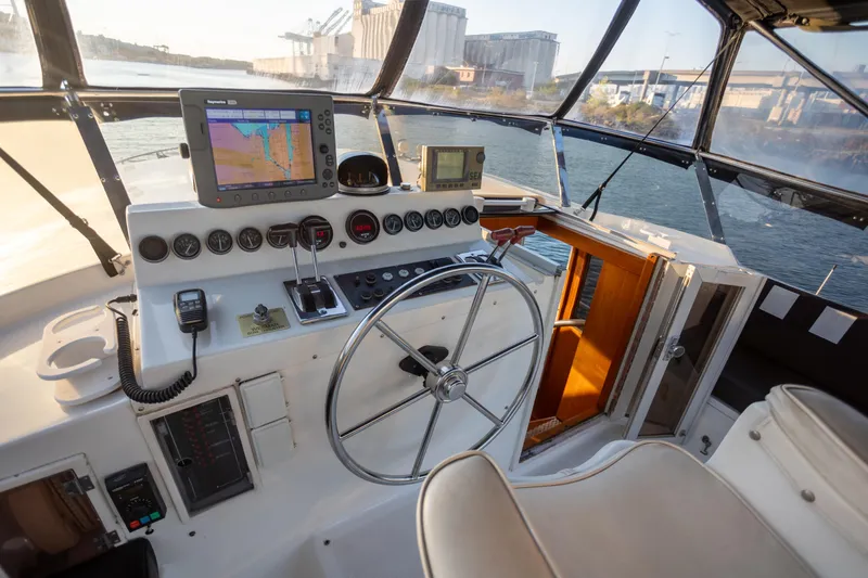 Mbellish Yacht Photos Pics 1988 Symbol 51 Motoryacht helm with navigation equipment and steering wheel, overlooking waterway.