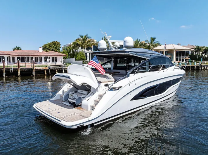 Endless Summer Yacht Photos Pics 2020 Princess V55 yacht docked by waterfront homes, featuring sleek design and American flag.