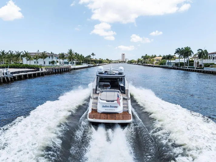 Endless Summer Yacht Photos Pics 2020 Princess V55 yacht cruising through a scenic canal with palm trees and luxury homes.