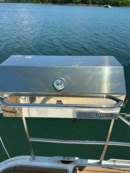 Stainless steel grill on 1991 Hunter Passage 42 sailboat, overlooking serene lake.