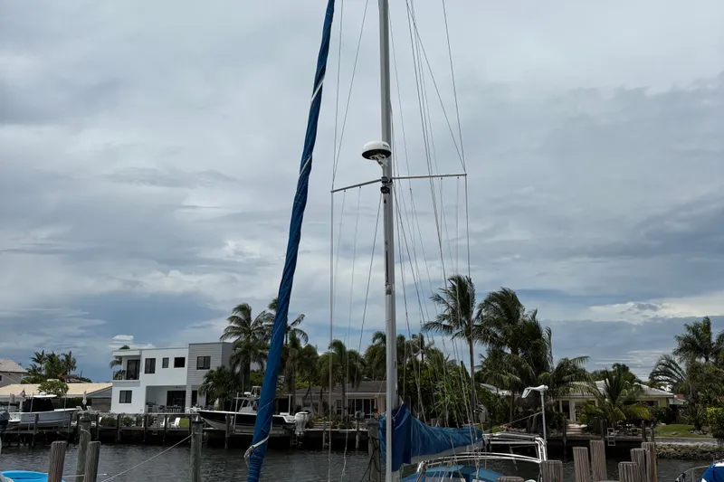 Otter Yacht Photos Pics Catalina 42 Mk II sailboat docked near waterfront homes, cloudy sky background.