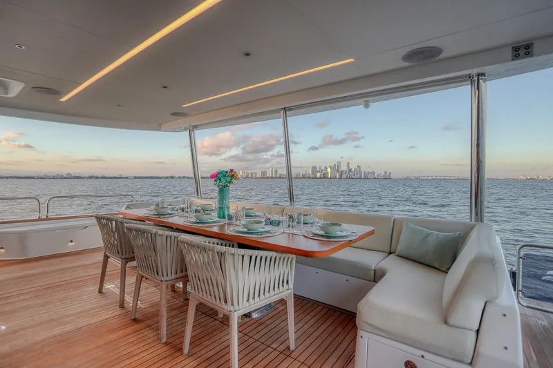 Our Trade Yacht Photos Pics Luxurious dining area on 2021 Sirena 88 yacht with city skyline view.
