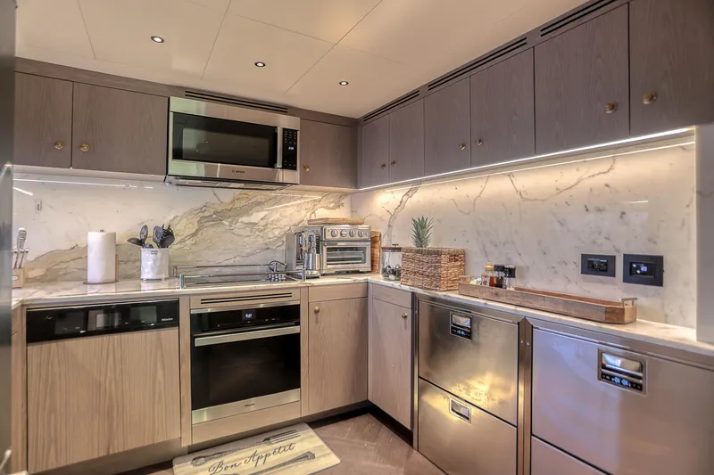 Our Trade Yacht Photos Pics Luxurious yacht kitchen with modern appliances, marble backsplash, and elegant cabinetry in a 2021 Sirena 88.