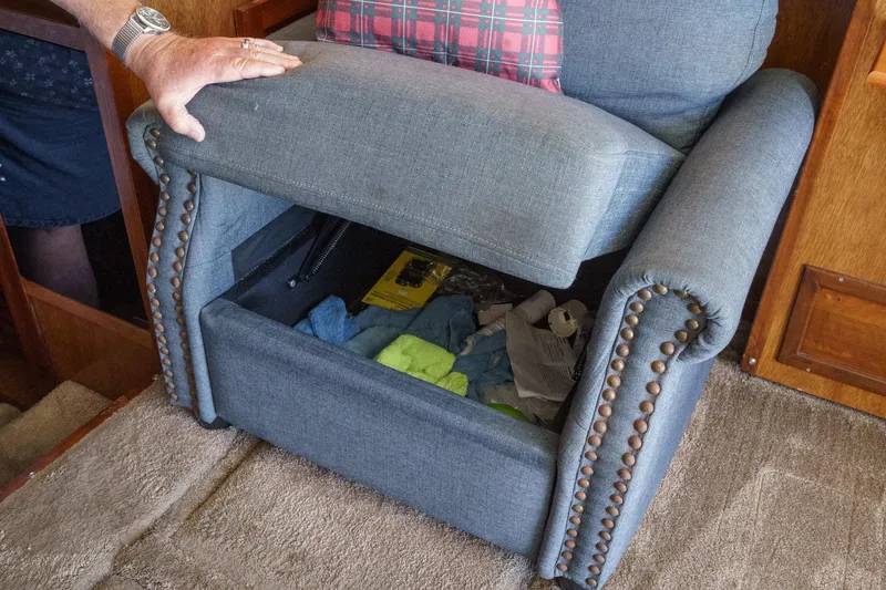  Yacht Photos Pics Blue armchair with hidden storage, revealing various items inside, on a 1974 Hatteras Convertible Sportfisher.