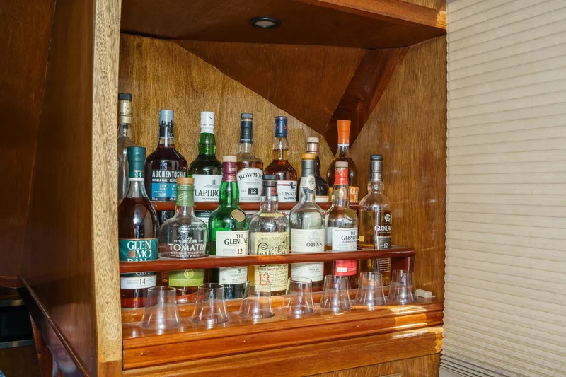  Yacht Photos Pics Collection of whiskey bottles in a wooden cabinet on a 1974 Hatteras Convertible Sportfisher.