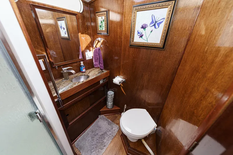  Yacht Photos Pics 1974 Hatteras Convertible Sportfisher bathroom with wood paneling, granite sink, and floral artwork.