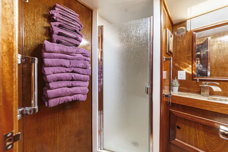  Yacht Photos Pics 1974 Hatteras Convertible Sportfisher bathroom with wooden decor, purple towels, and glass shower door.