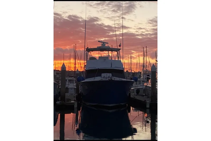  Yacht Photos Pics 1974 Hatteras Convertible Sportfisher at sunset in marina, silhouetted against vibrant sky.