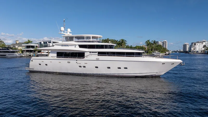 Kaya Yacht Photos Pics Luxurious 2003 Johnson 87 yacht cruising on a sunny day, surrounded by waterfront properties.