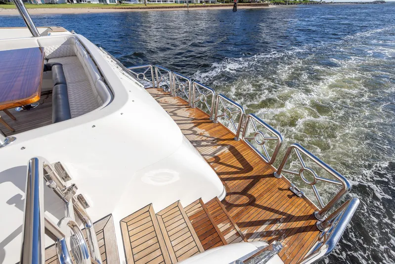 Kaya Yacht Photos Pics Luxury yacht deck with wooden flooring, stainless steel railings, and scenic water view. Johnson 87, 2003 model.