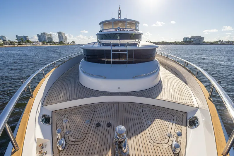 Kaya Yacht Photos Pics Luxury Johnson 87 yacht, 2003 model, cruising on open water with modern cityscape in background.