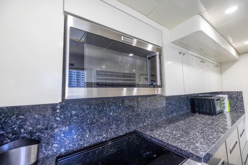 Kaya Yacht Photos Pics Modern kitchen with stainless steel microwave, granite countertops, and white cabinetry. Johnson 87, 2003 model.