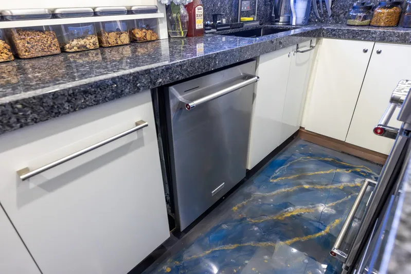 Kaya Yacht Photos Pics Modern kitchen with granite countertops, stainless steel appliances, and a unique blue and gold epoxy floor.