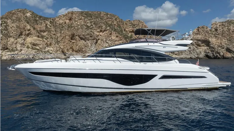  Yacht Photos Pics Luxury 2022 Princess S66 yacht cruising near rocky coastline under blue sky.