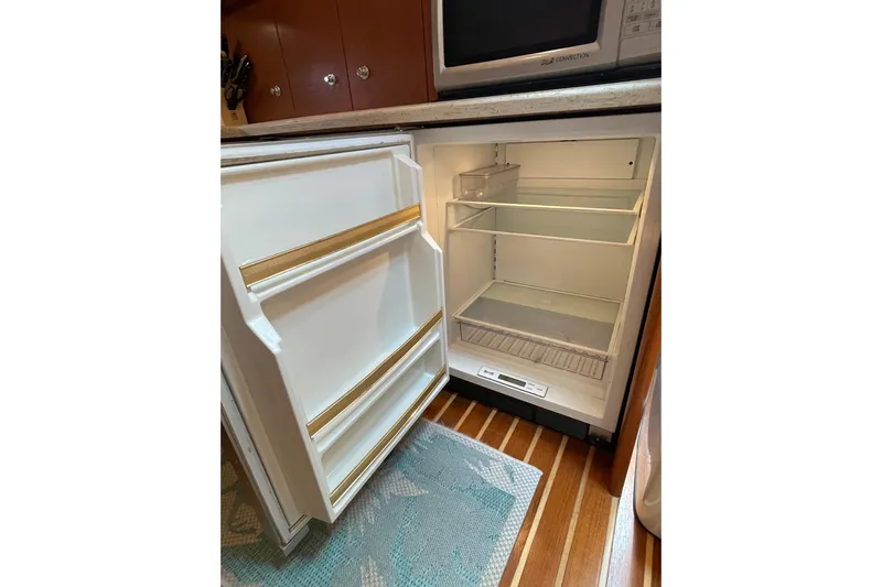 Sasea Yacht Photos Pics Open refrigerator in 2009 Tiara Yachts 4200 Open, showcasing interior shelves and wooden flooring.
