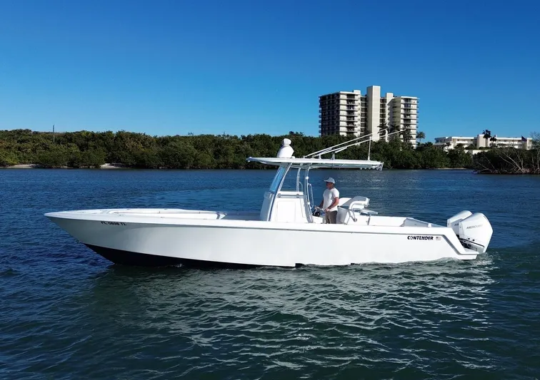 Yacht Photos Pics 2023 Contender 32 ST boat on water, clear sky, buildings in background.