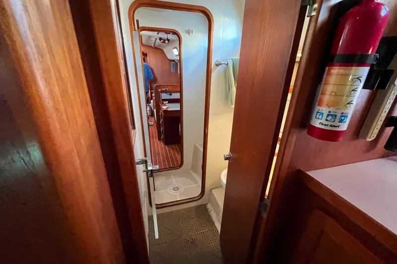 "destination Unknown" Yacht Photos Pics Interior of 1985 Caliber 47LRC yacht showing bathroom and cabin with wooden finishes.