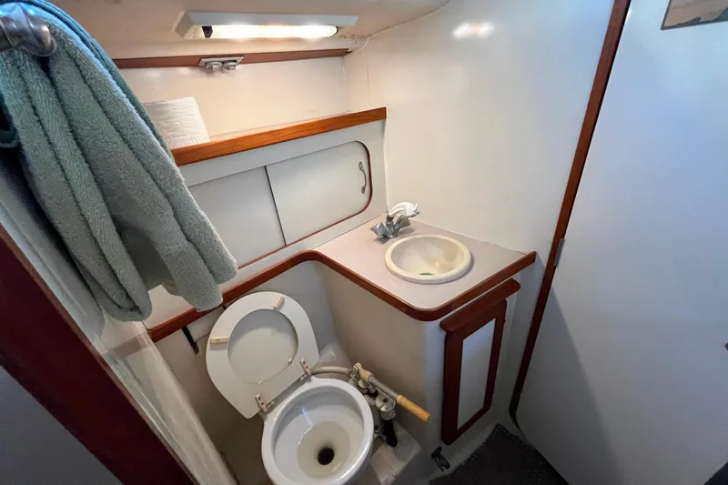 "destination Unknown" Yacht Photos Pics Compact bathroom in 1985 Caliber 47LRC yacht with sink, toilet, and storage.