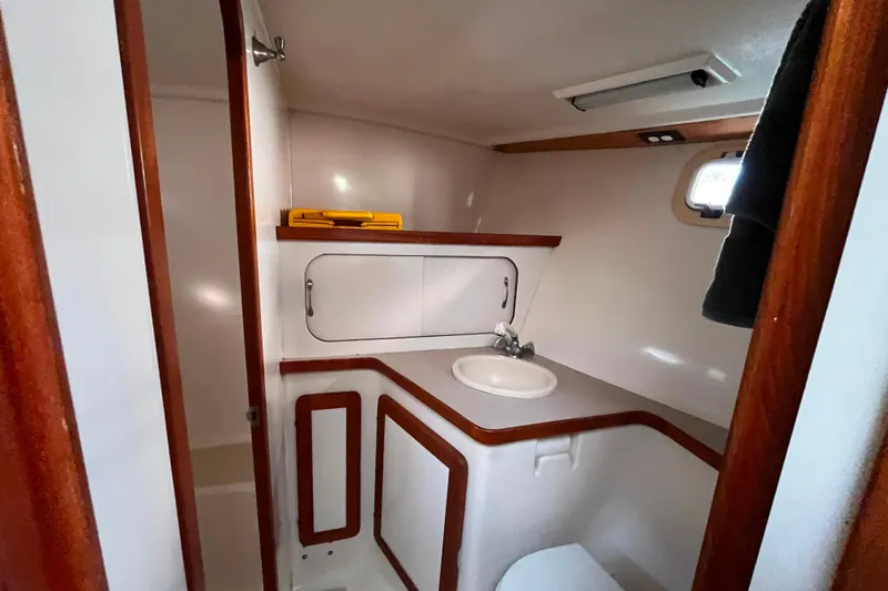 "destination Unknown" Yacht Photos Pics Bathroom interior of 1985 Caliber 47LRC yacht with sink and wooden accents.