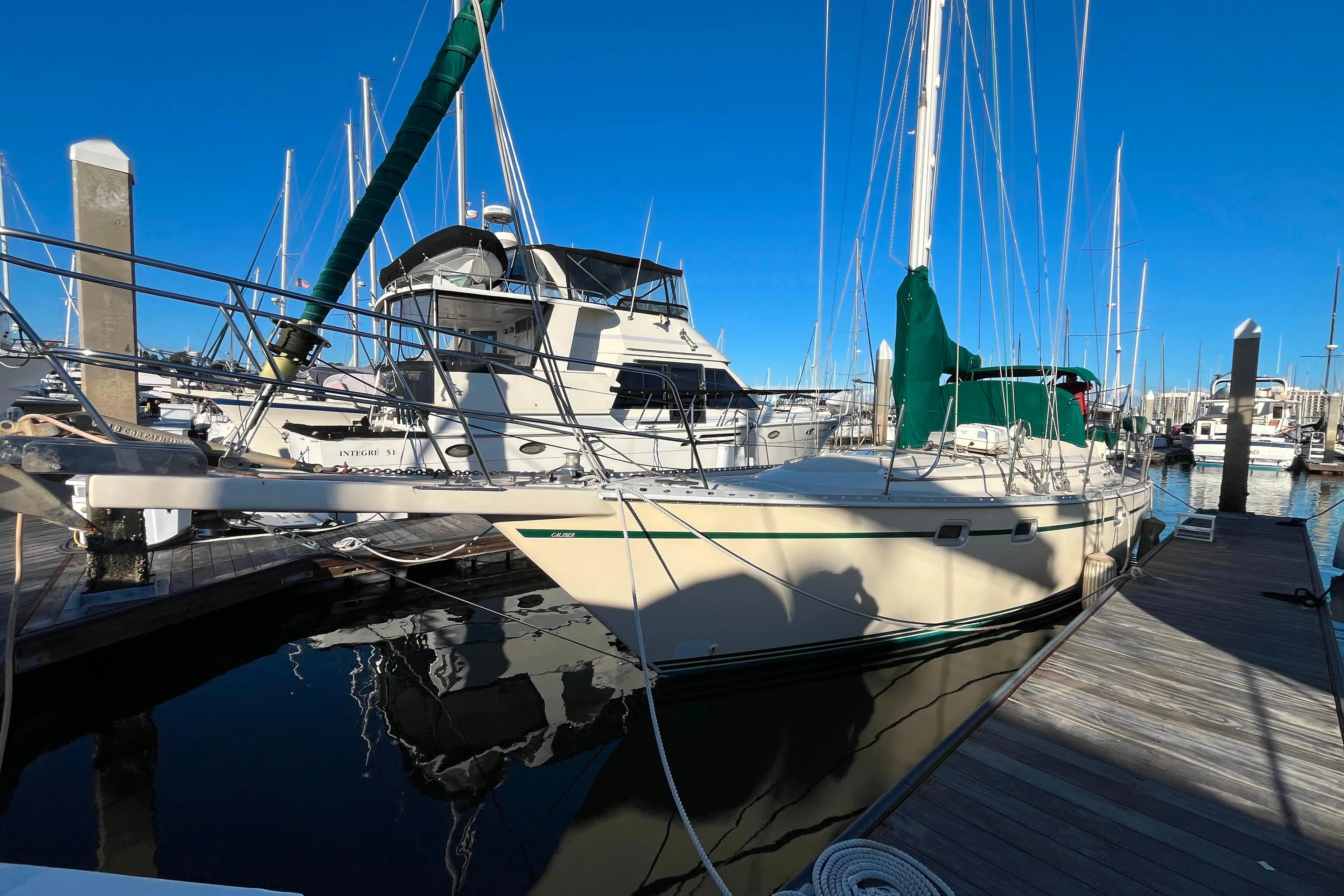 1985 Caliber 47LRC sailboat docked at marina under clear blue sky.