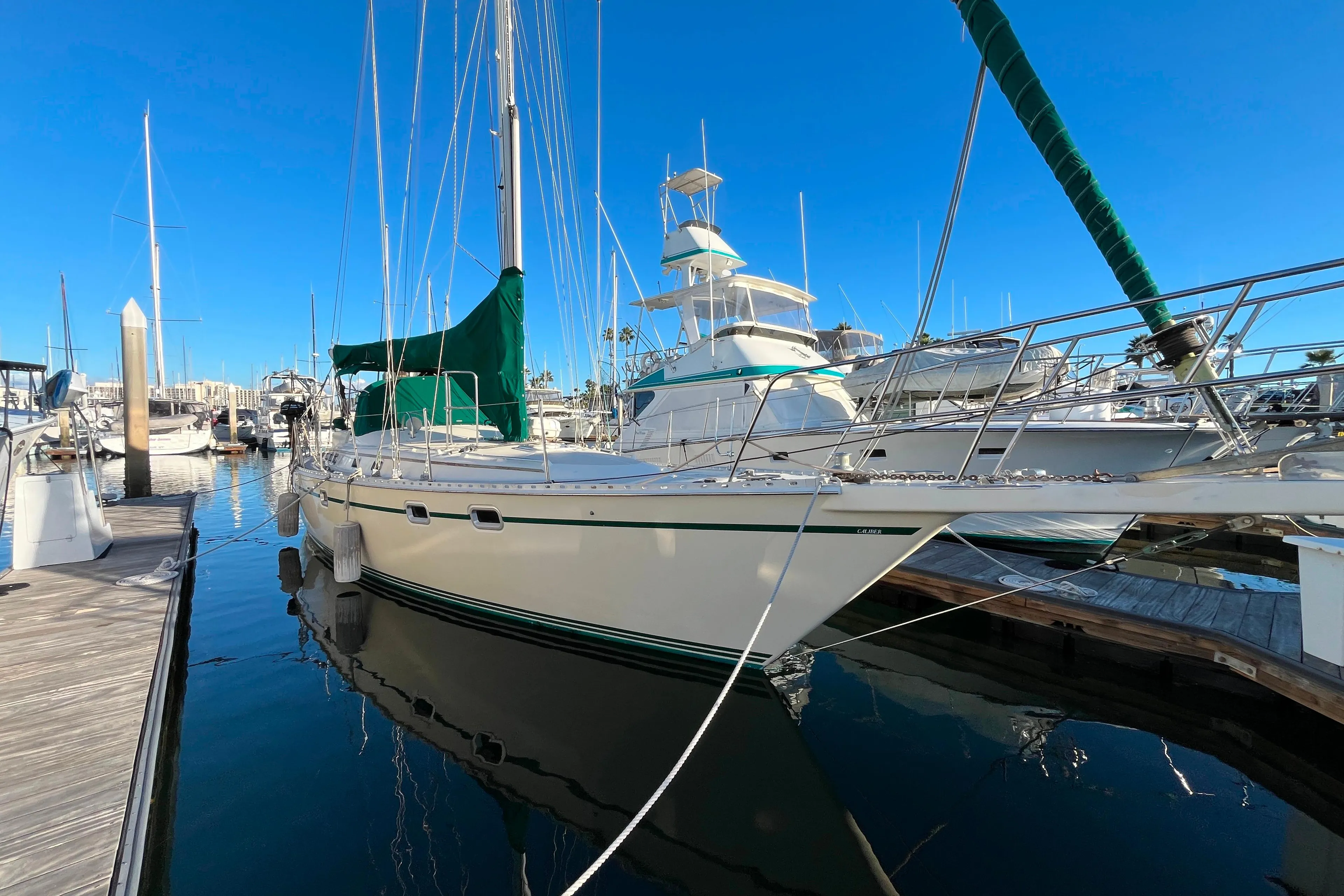 1985 Caliber 47LRC sailboat docked in marina, clear blue sky, calm water.